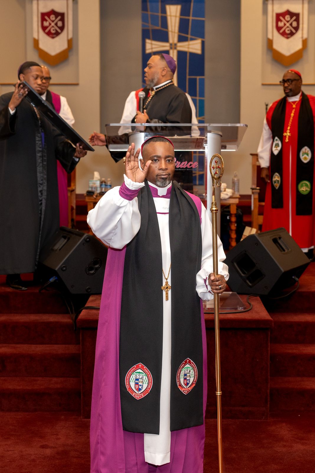 Bishop Edward Jones, IV in his episcopal robes, holding a crozier and raising his hand in blessing