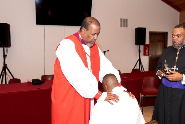A bishop in red with his hands on the shoulders of the Bishop-elect