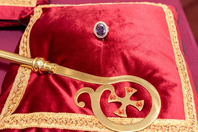 A ring and the head of a crozier resting on a red pillow