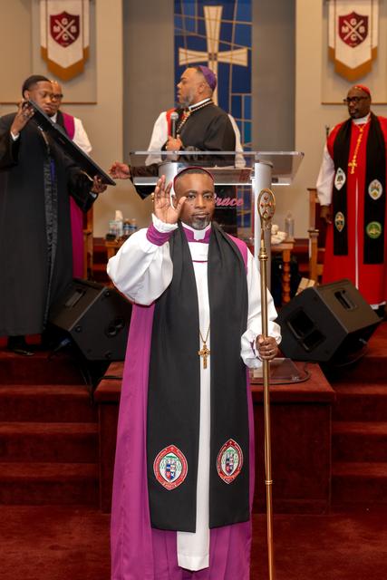 Bishop Jones in his episcopal robes, holding a crozier and raising his hand in blessing